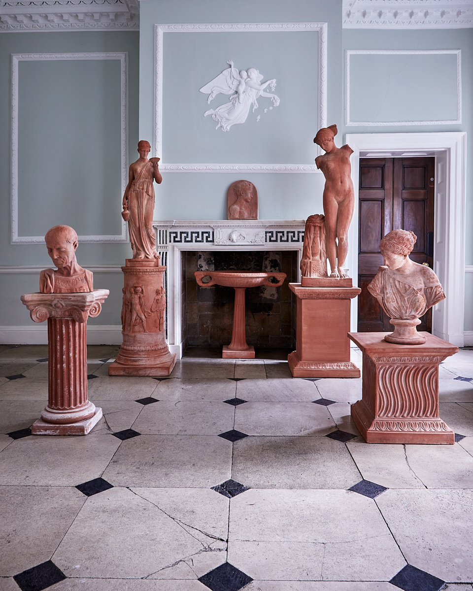 Georgian hallway with terracotta statues and busts surrounding an original fireplace